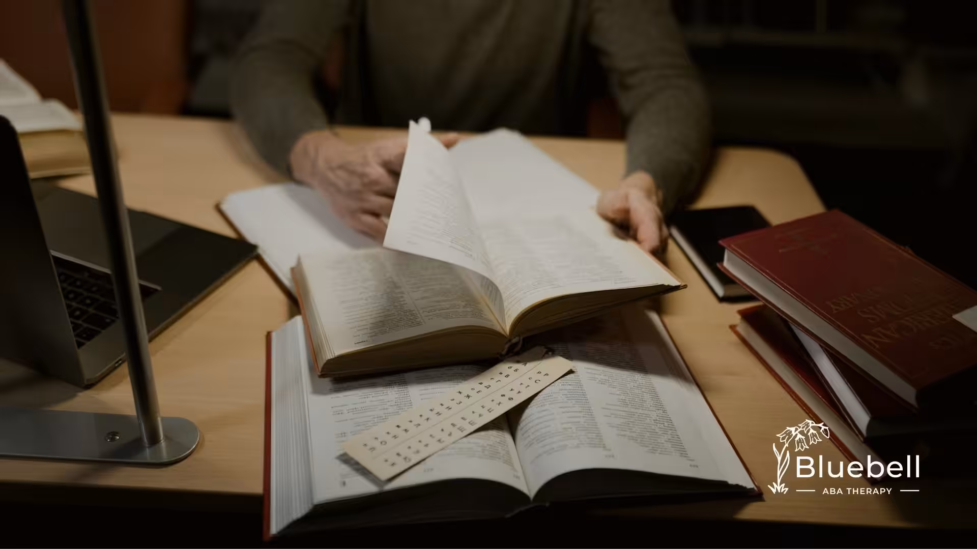 A BCBA aspirant flipping through a BCBA exam resources on a desk, surrounded by reference materials as part of their BCBA exam study guide.