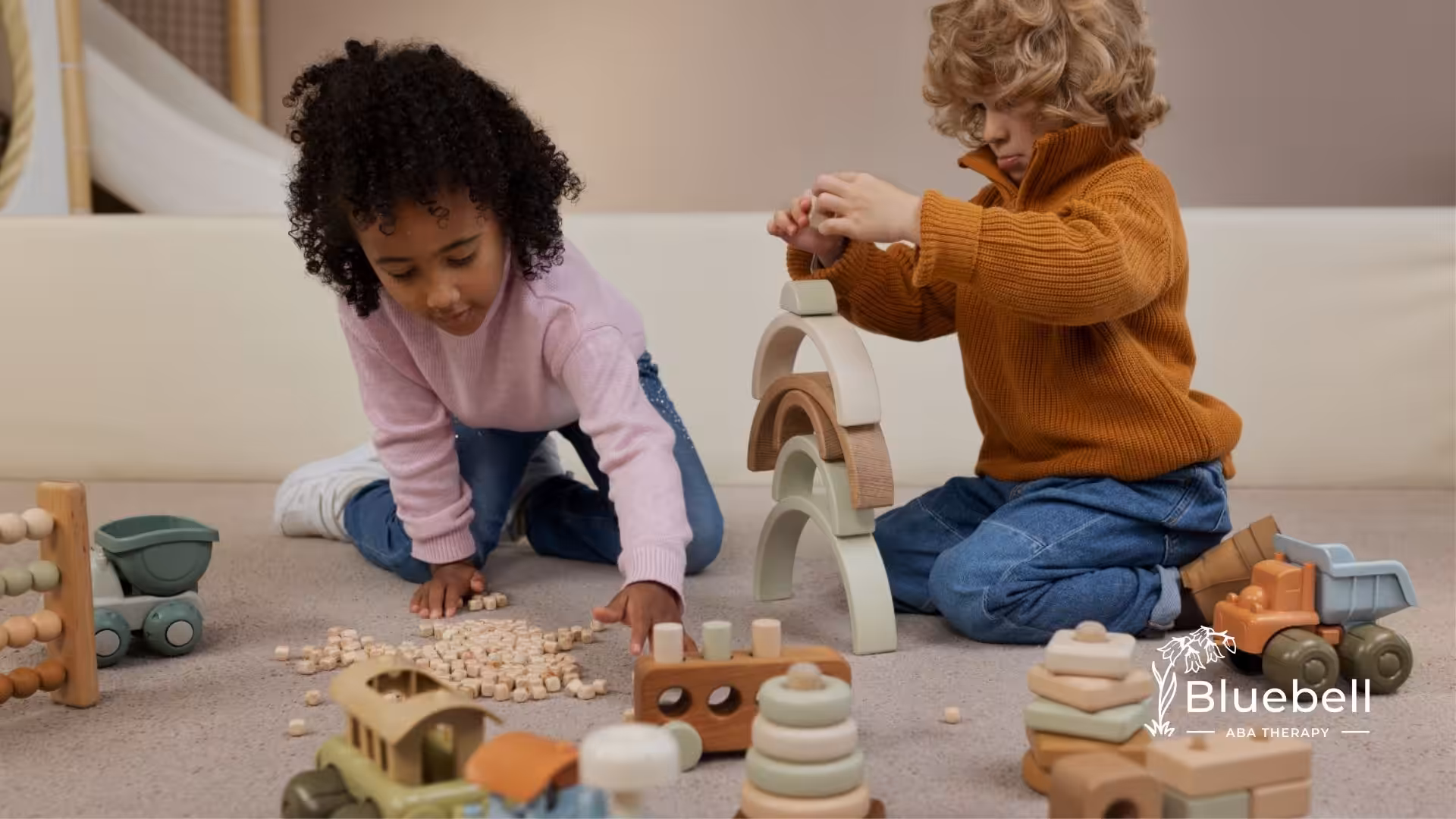 Two children building and arranging wooden toys on the floor in a cozy room.
