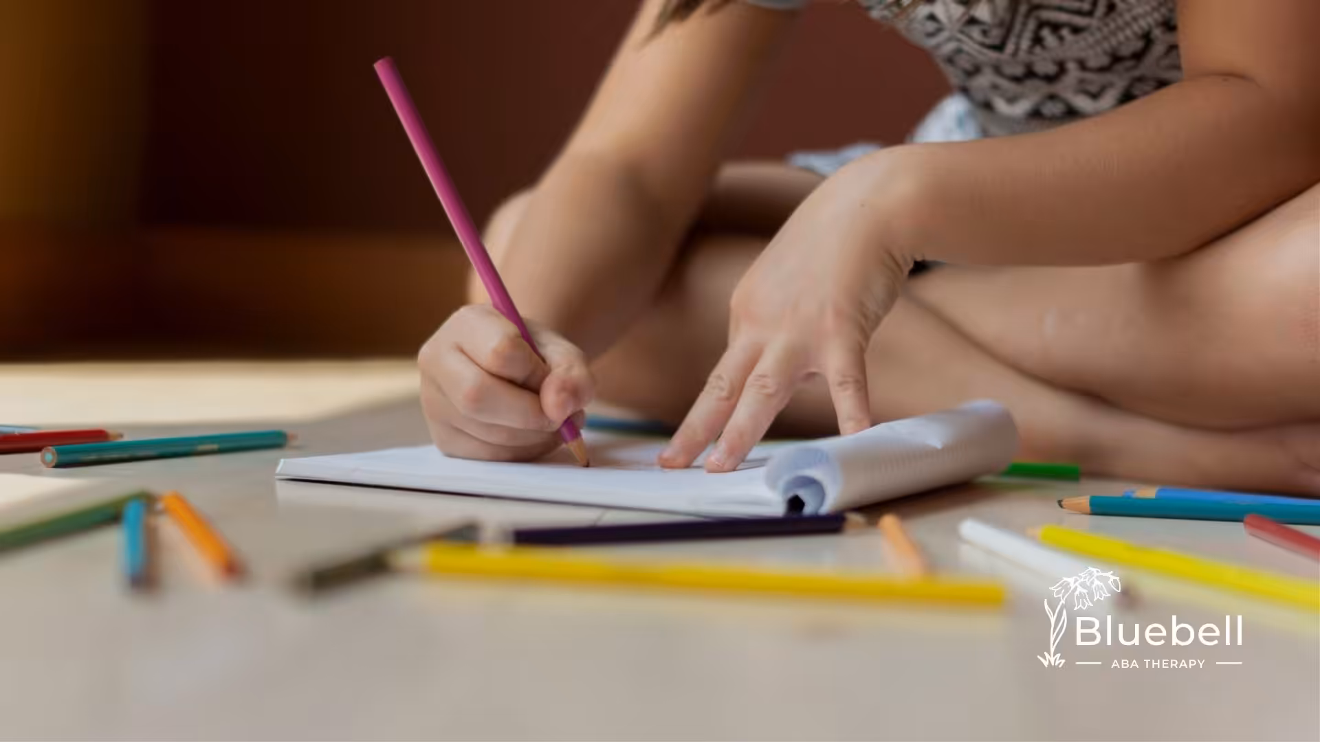 Child with autism drawing with colored pencils, surrounded by scattered crayons in North Carolina.