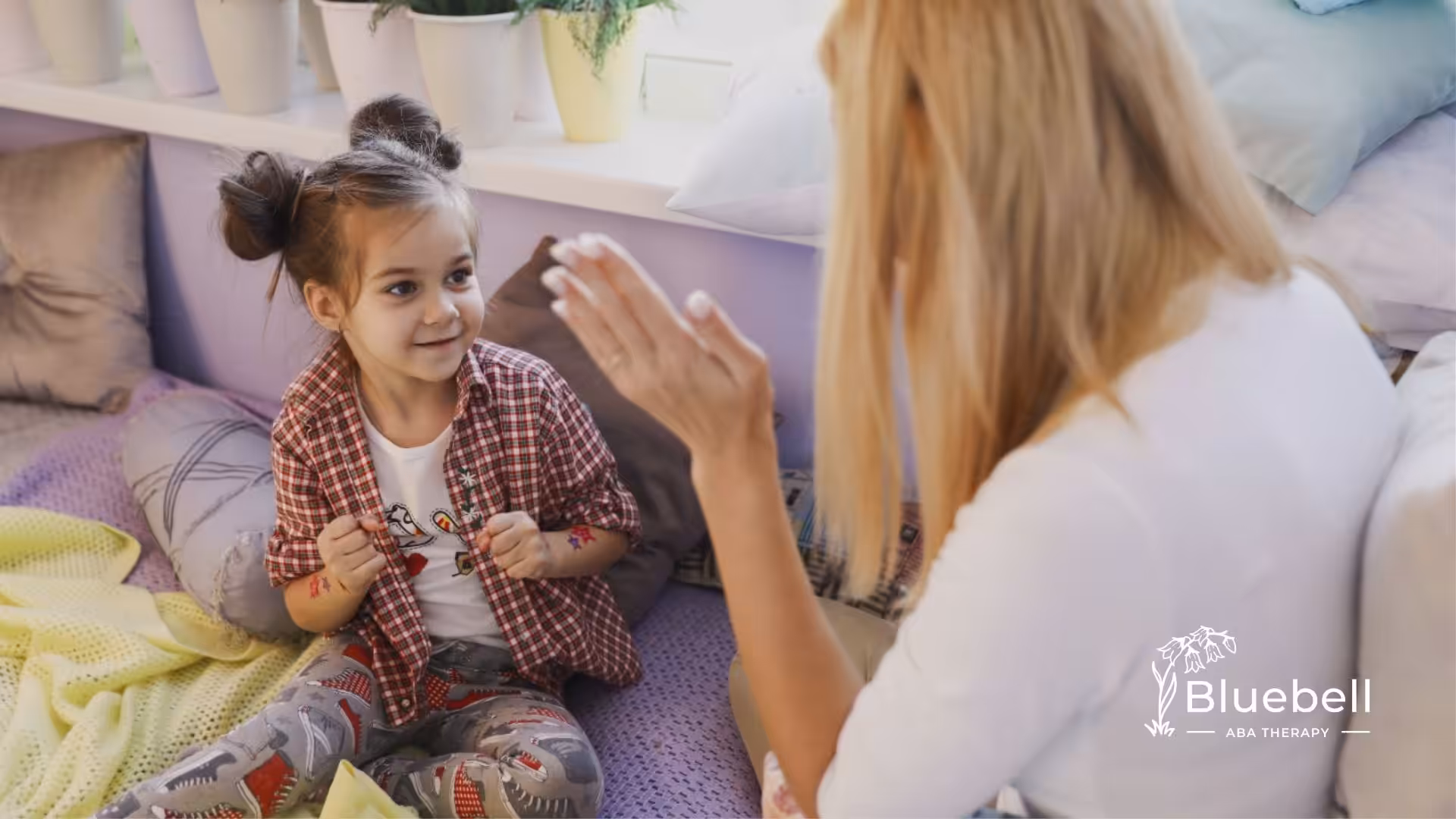 A smiling young girl engaging in a playful activity with an ABA therapist in a cozy room.