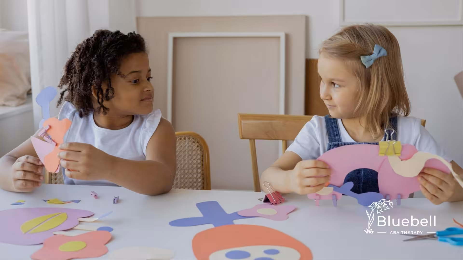 Two children part of autism support group in NC crafting with paper cutouts while sitting at table.