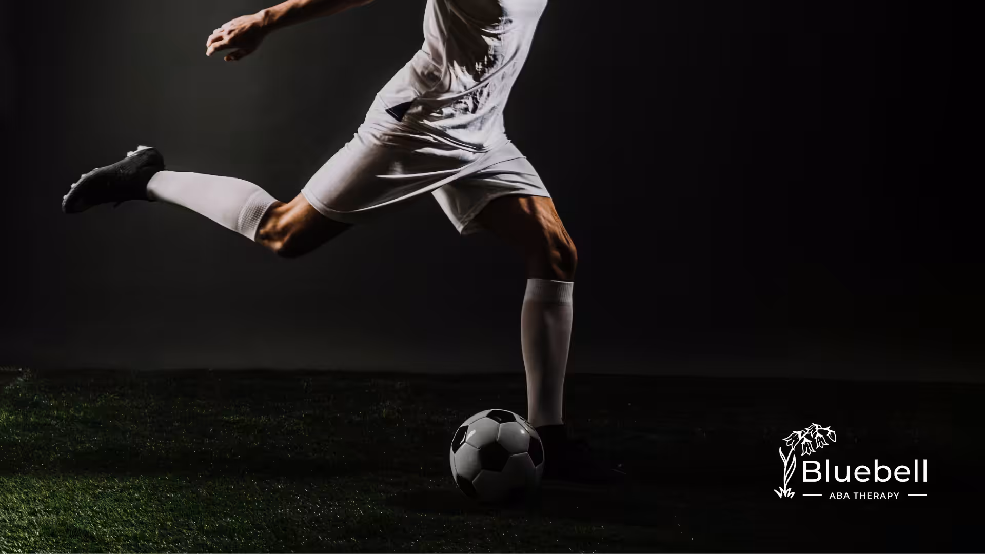 A professional footballer is kicking a football on a field