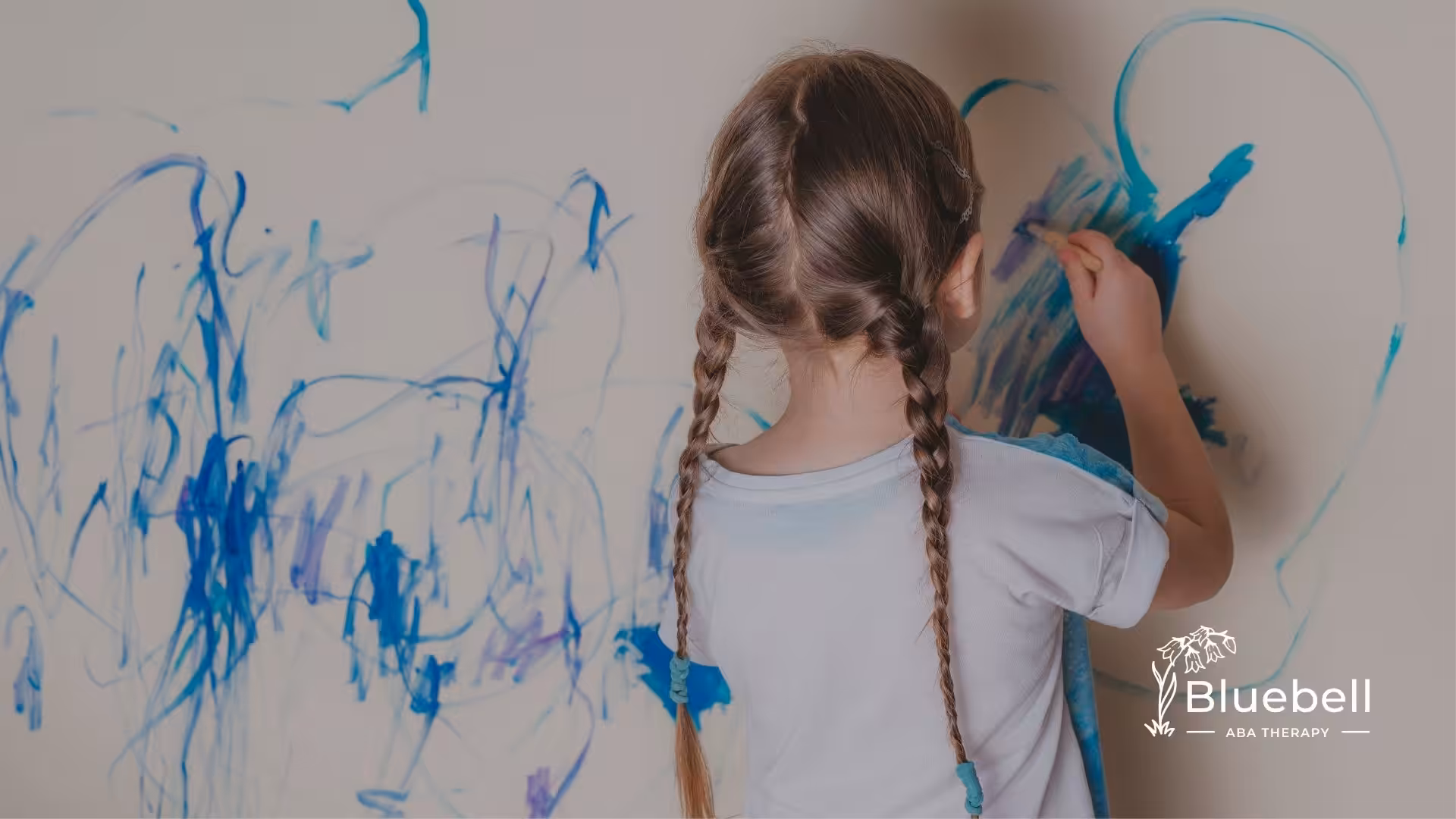 A little girl with autism drawing on the wall.