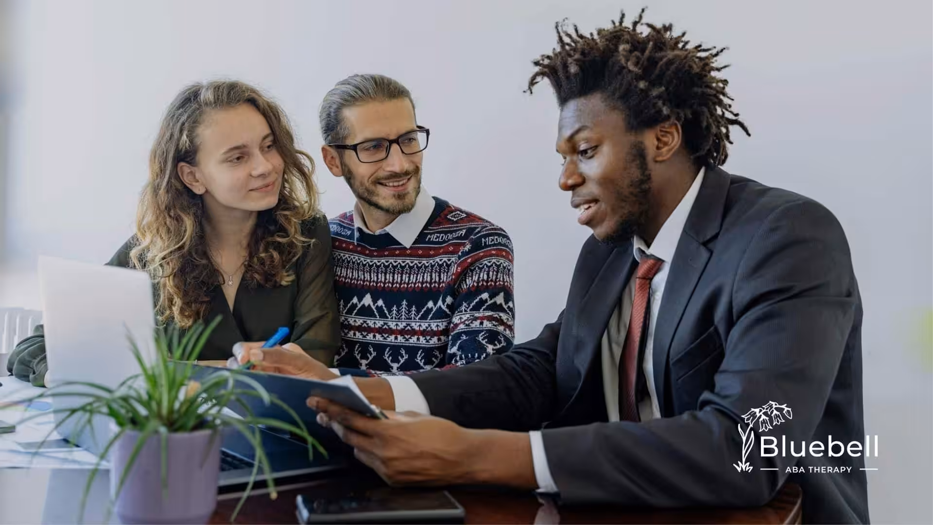 Financial advisor explaining ABA therapy laws to smiling parents at office desk in North Carolina.