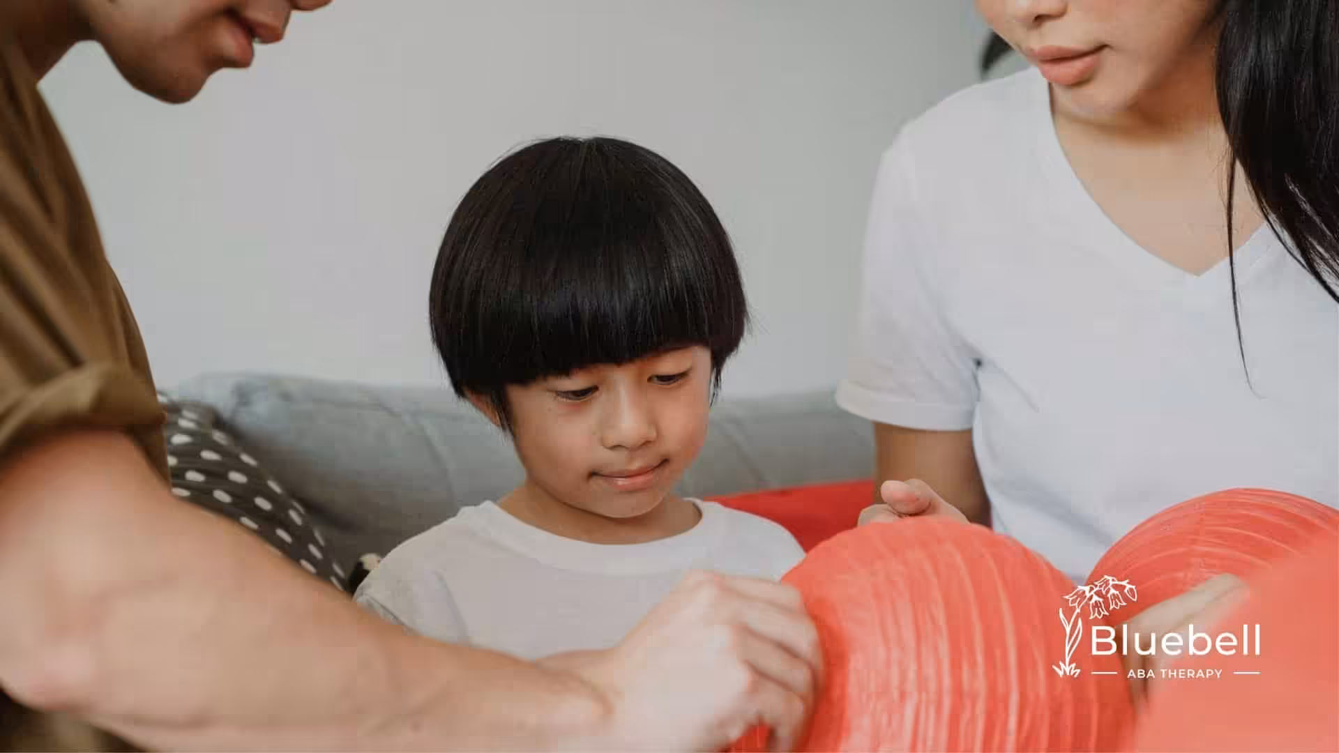 An autistic child with short black hair decorating a red paper lantern with family members in NC.