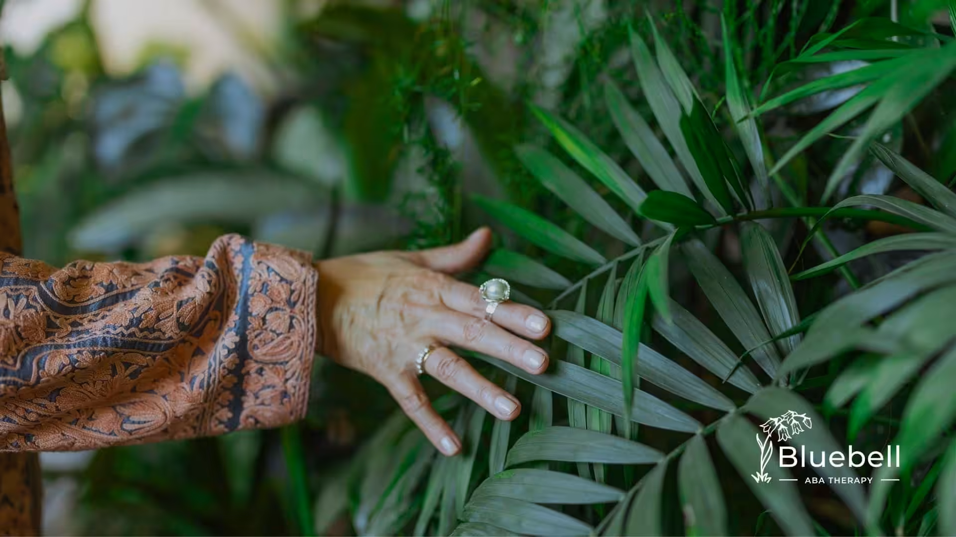 A woman touches the leaves of a palm tree