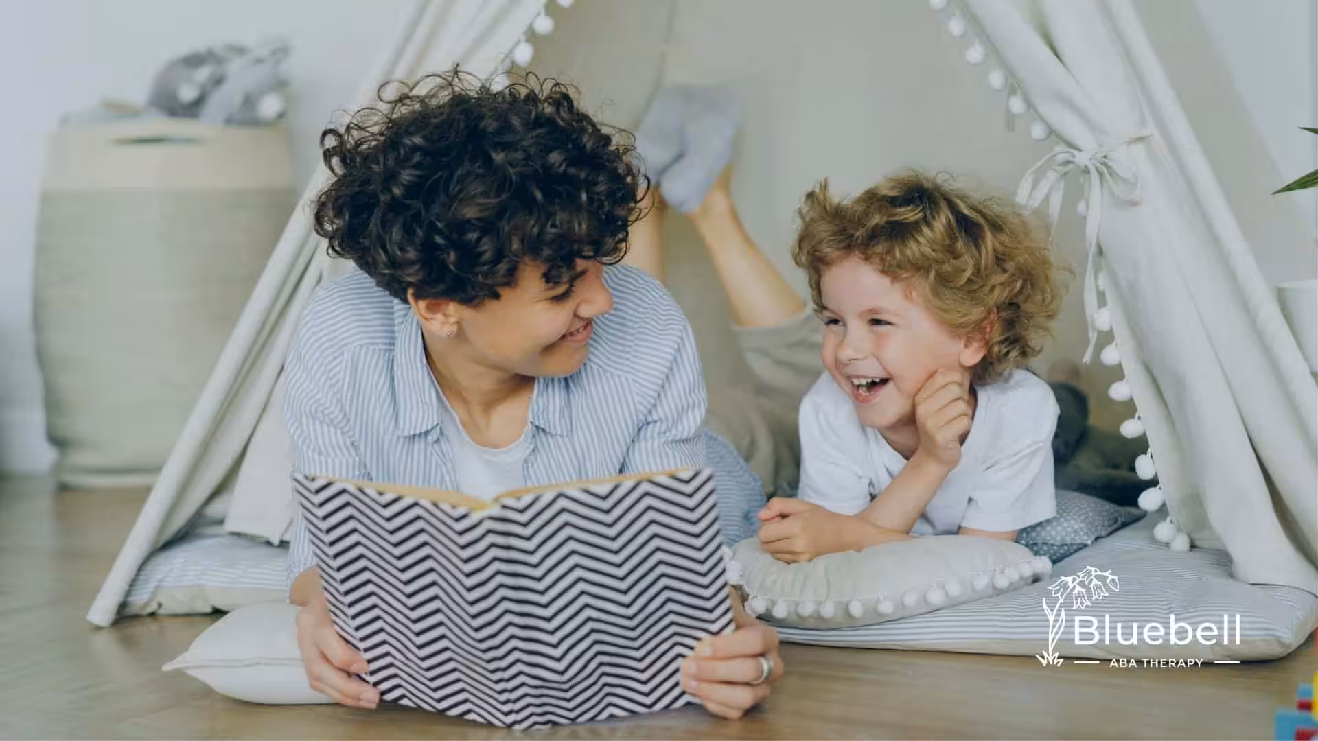 RBT reading a book with an autistic child inside a cozy play tent during in-home ABA therapy in NC.
