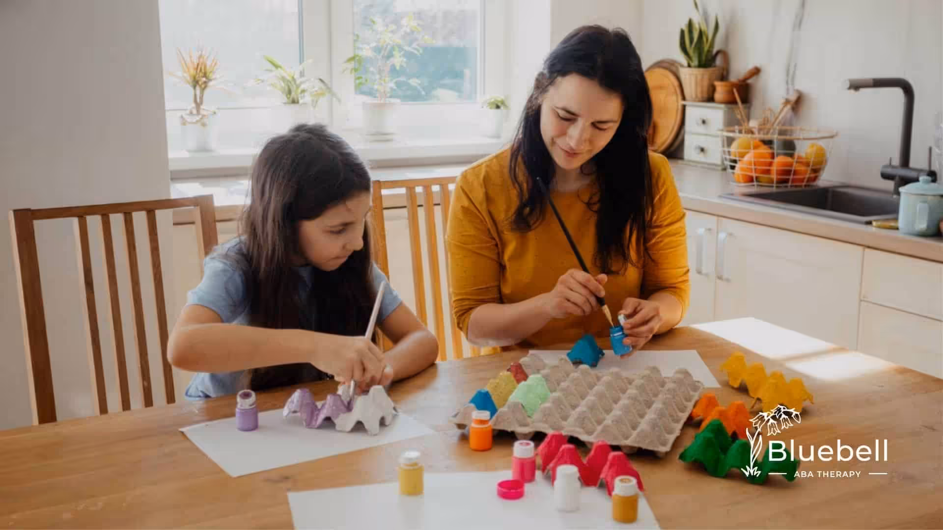 ABA therapist painting colorful egg cartons at a table.