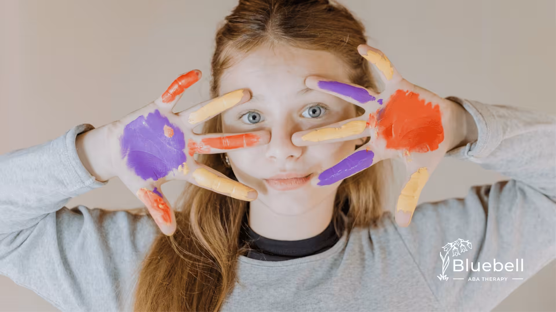 A girl holding her painted hands up her face