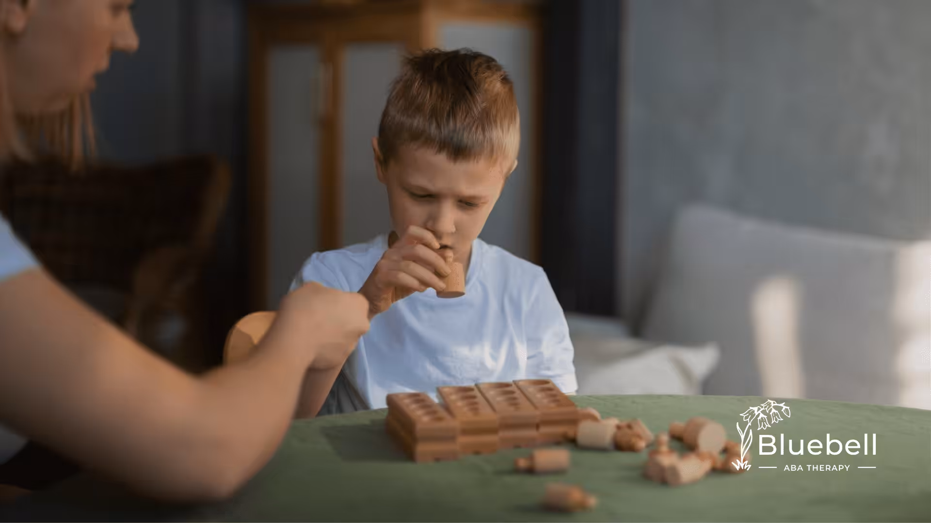 A child with autism and an ABA therapist are playing with wooden blocks