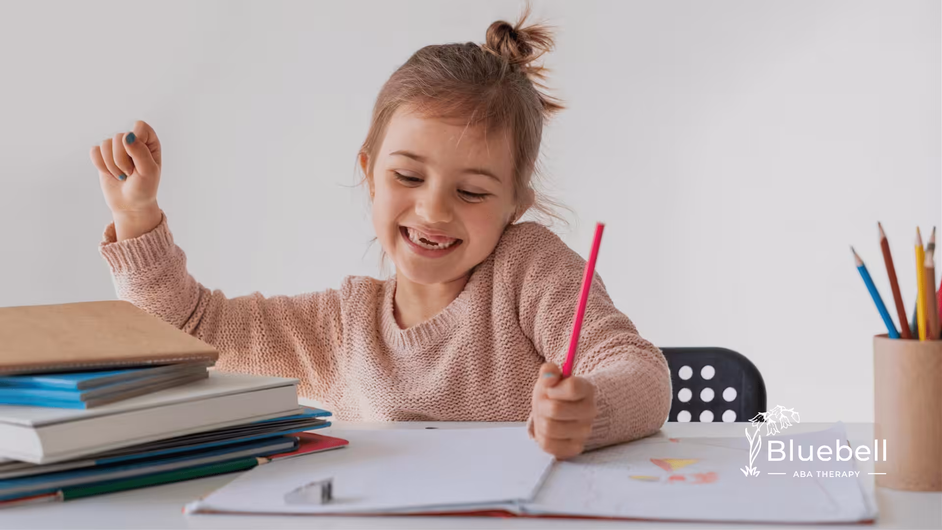 A child with autism is smiling while writing on a paper