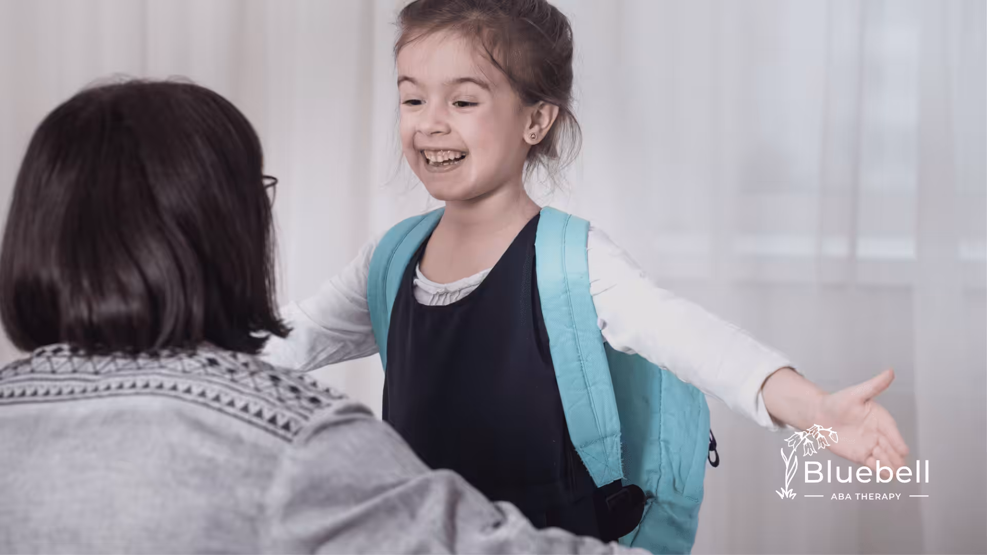An autistic child wearing a backpack smiling at her mother