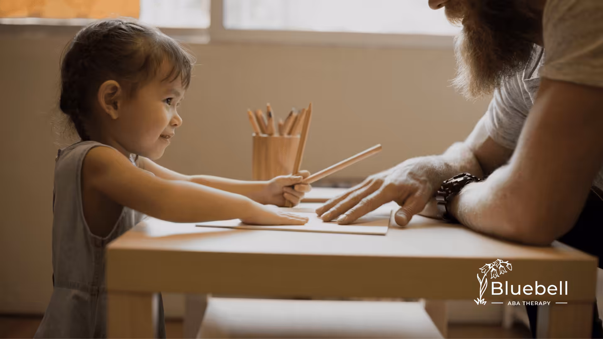 A neurodiverse child is writing on a table with her parent