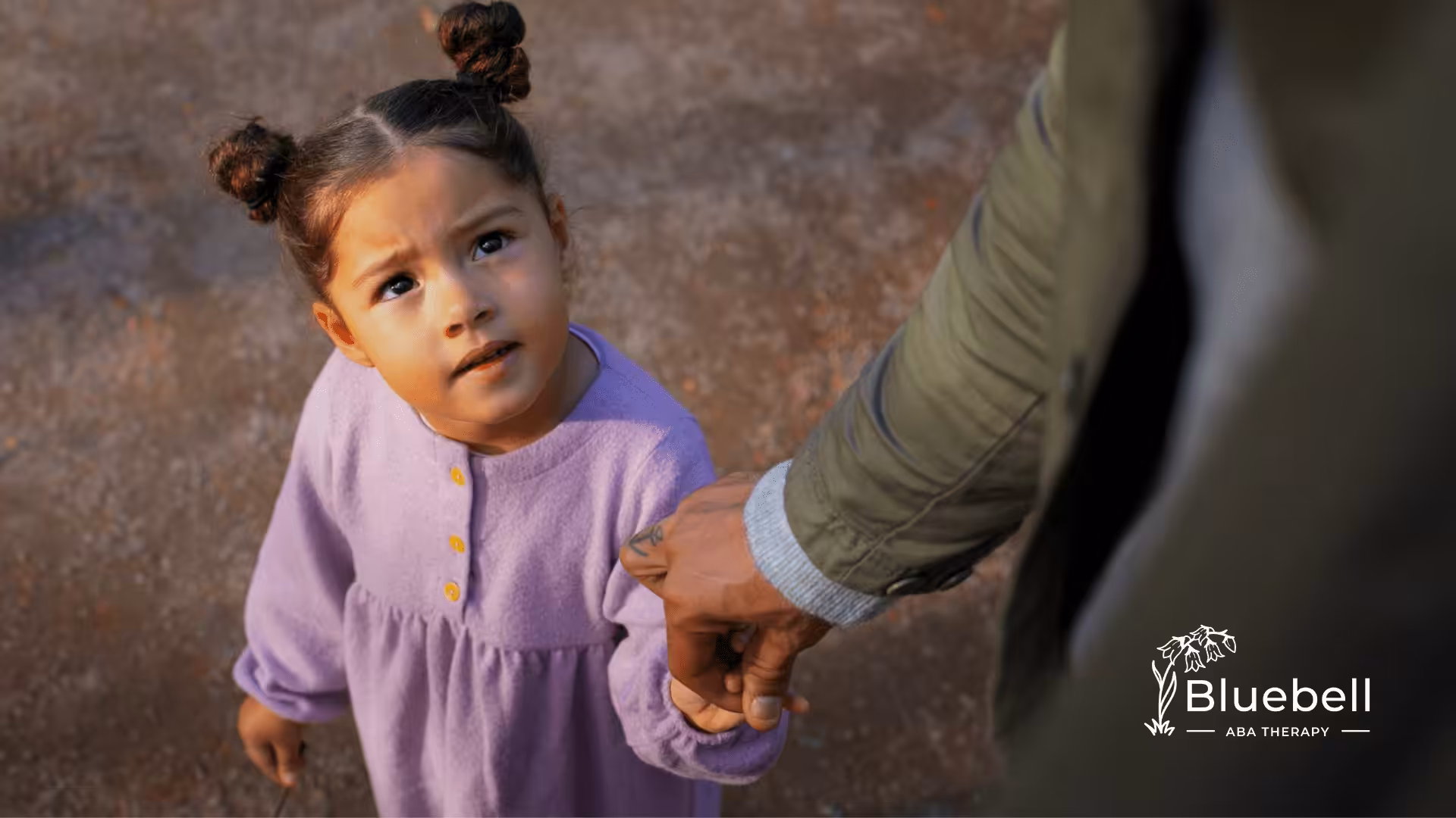 A child with autism is holding her parent's hand