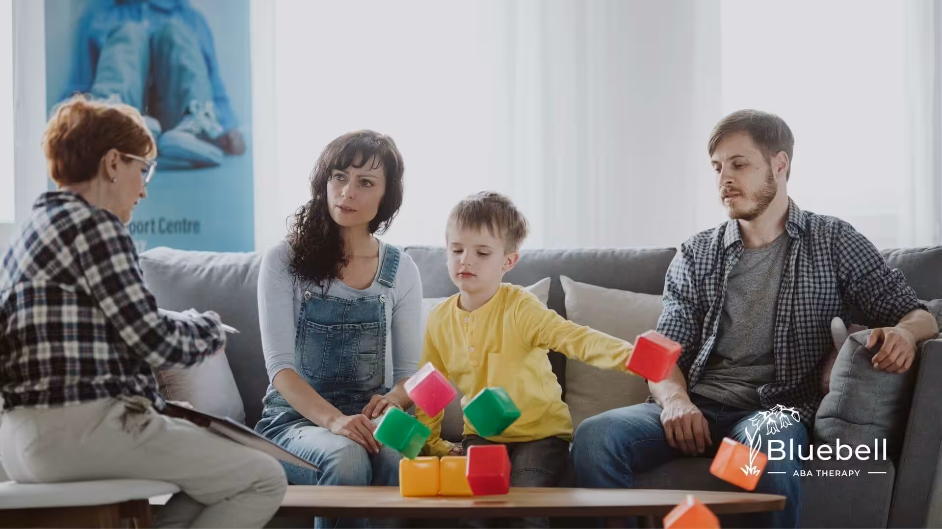Family and ABA therapist working with autistic child using colorful blocks.