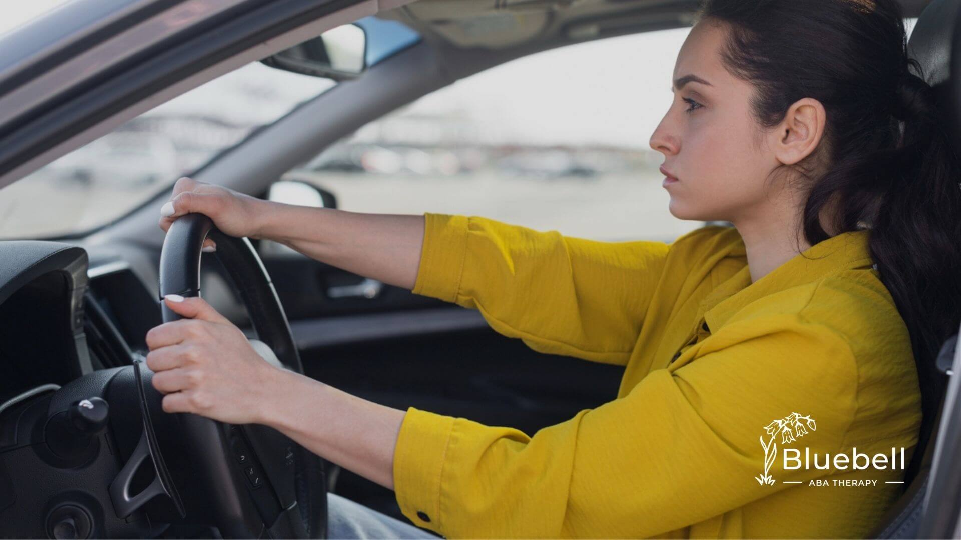 A woman with autism in a yellow shirt driving a car.