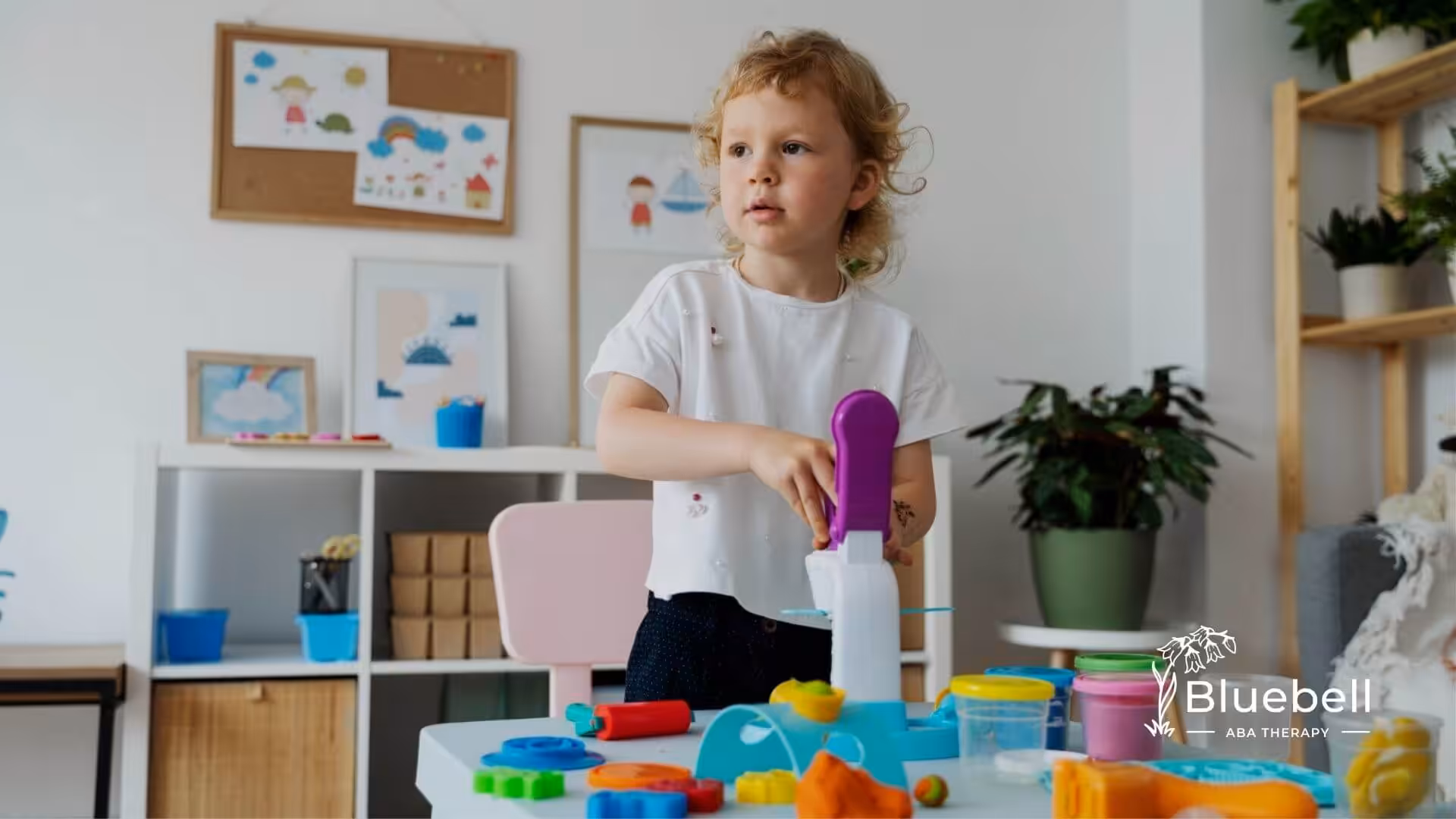 Autistic girl playing with playdough tools at a table in ABA therapy.