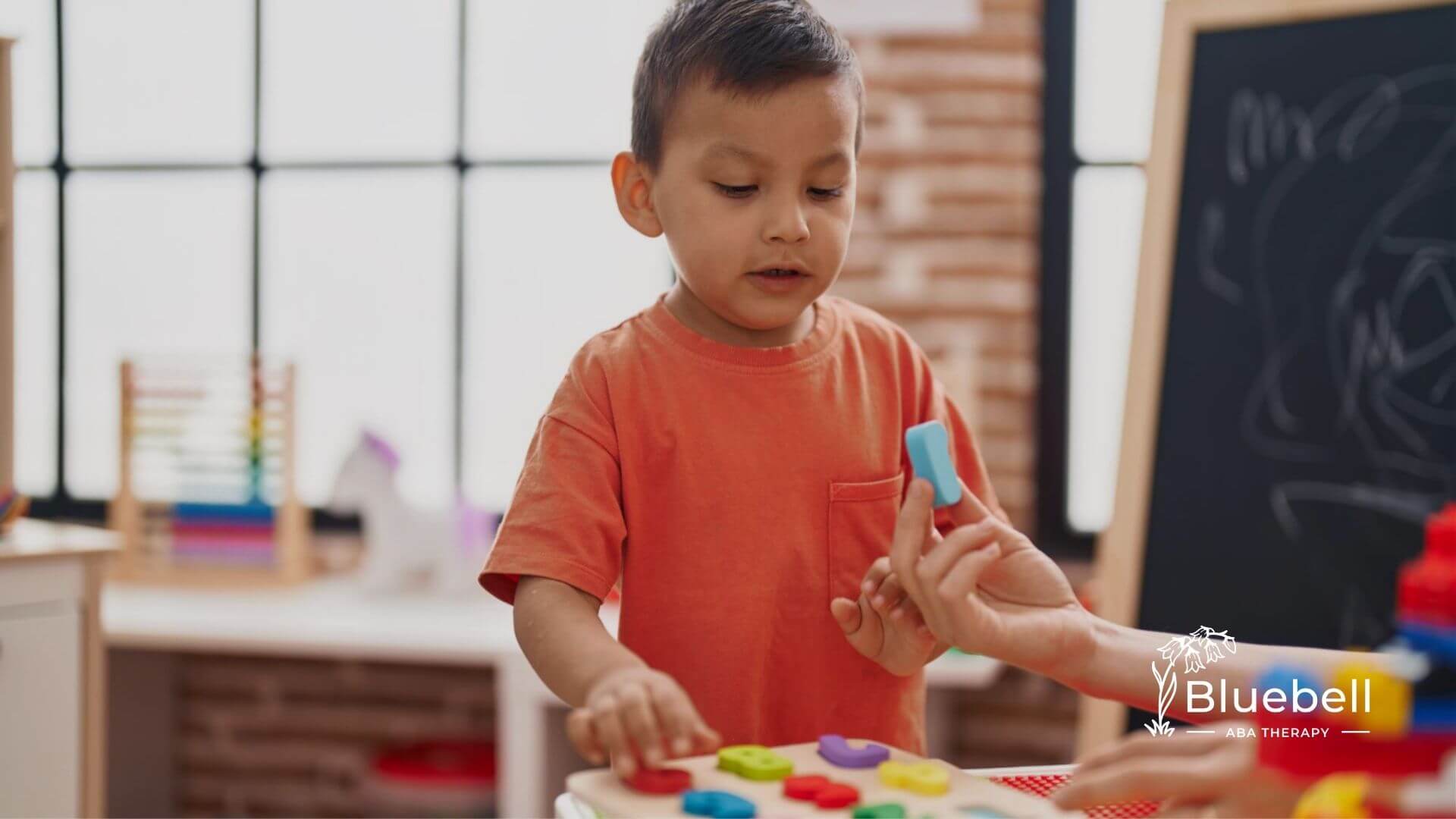 Child playing with colorful shape puzzle in an ABA therapy center.