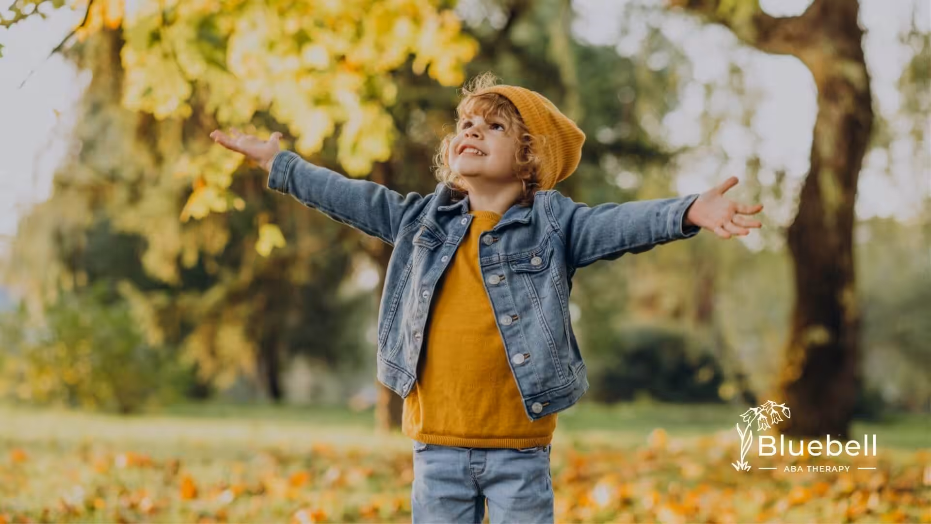 Autistic child in park with arms outstretched.