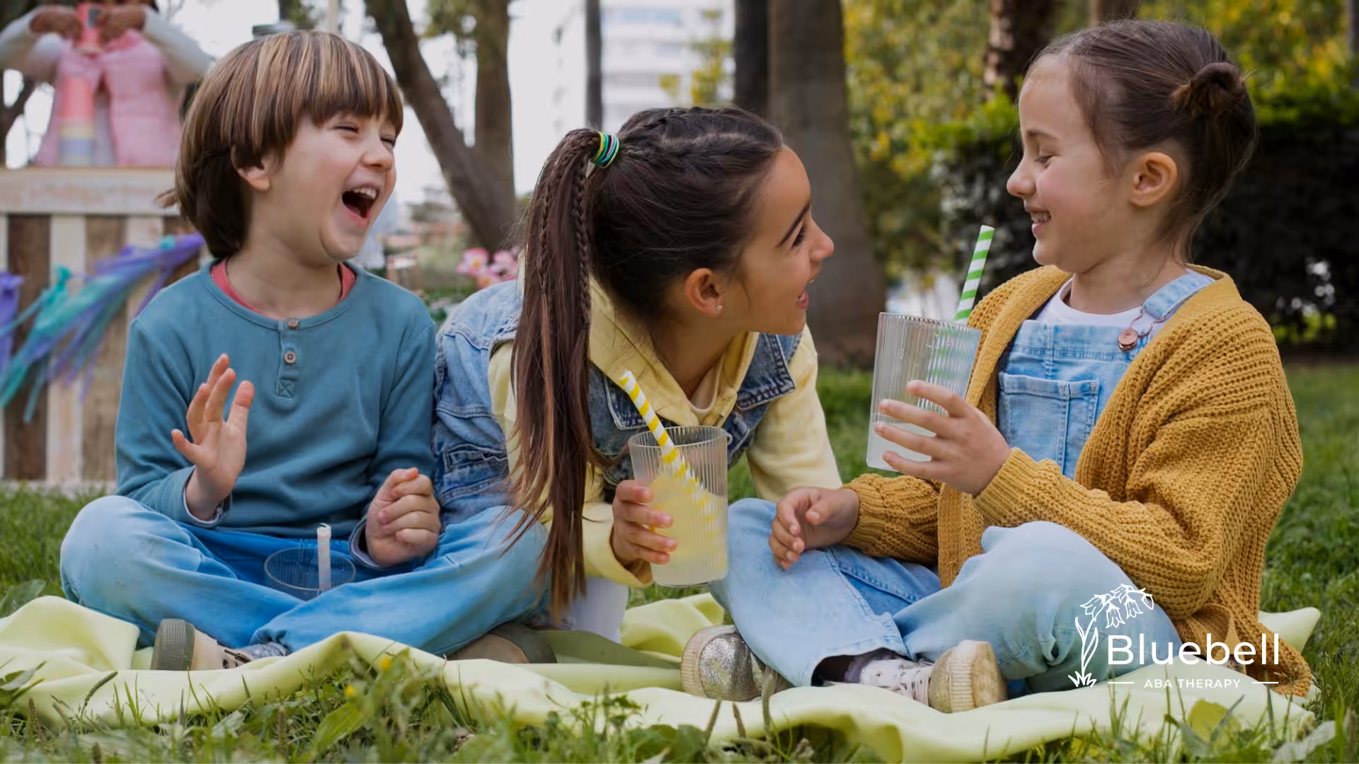 Three kids sitting on the grass talking to each other