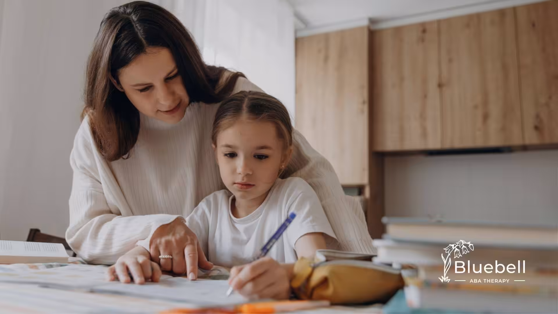 An ABA therapist and autistic child working on a drawing at a table in ABA therapy.