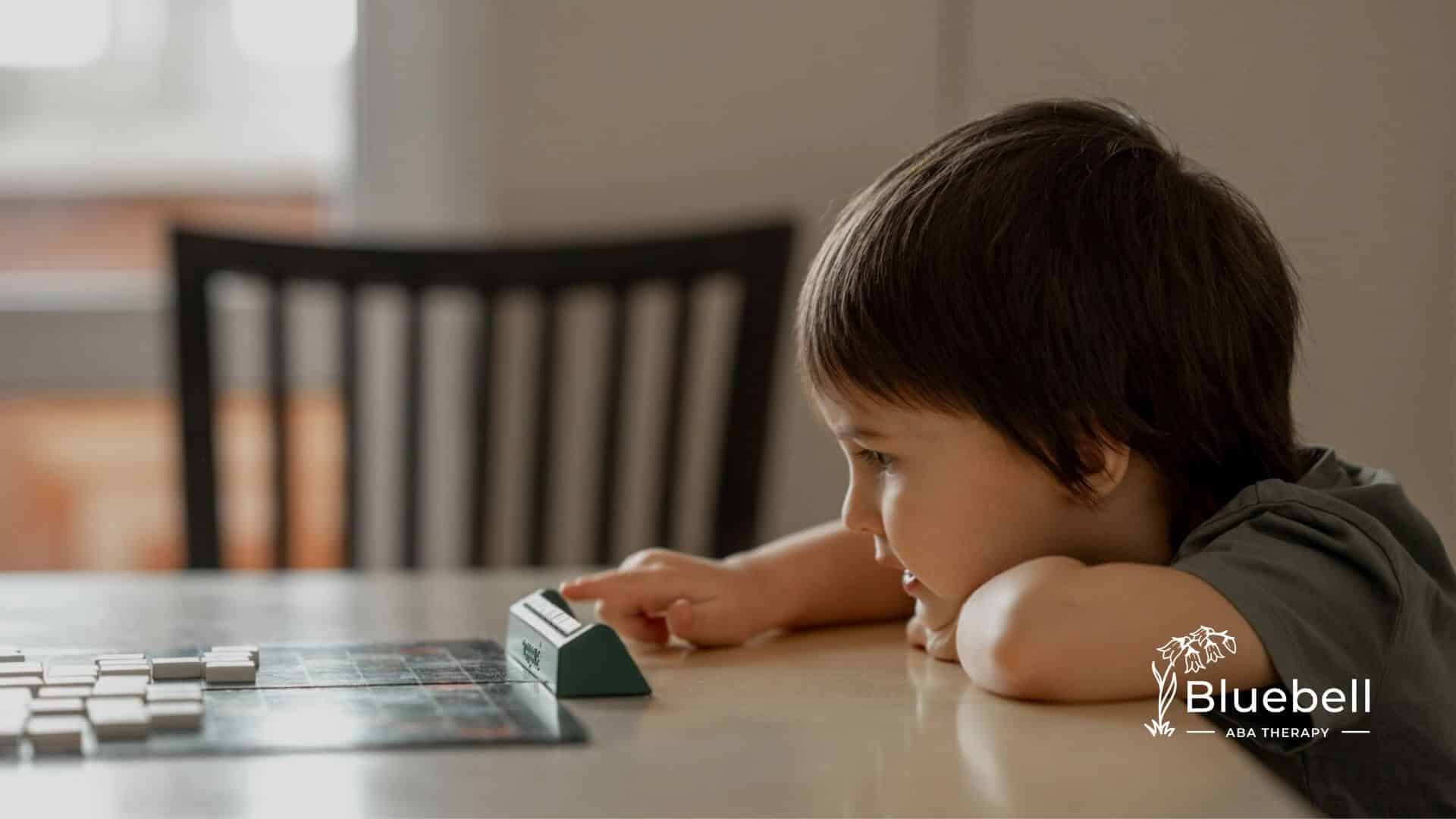 A young boy with autism focused on playing a board game on a table.