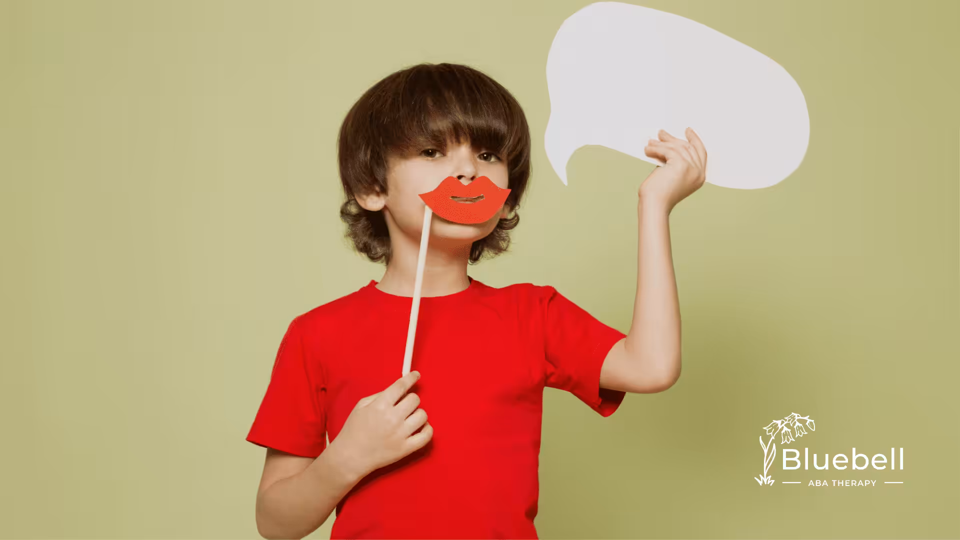 A kid with autism holding a cutout of a speech bubble and a lips