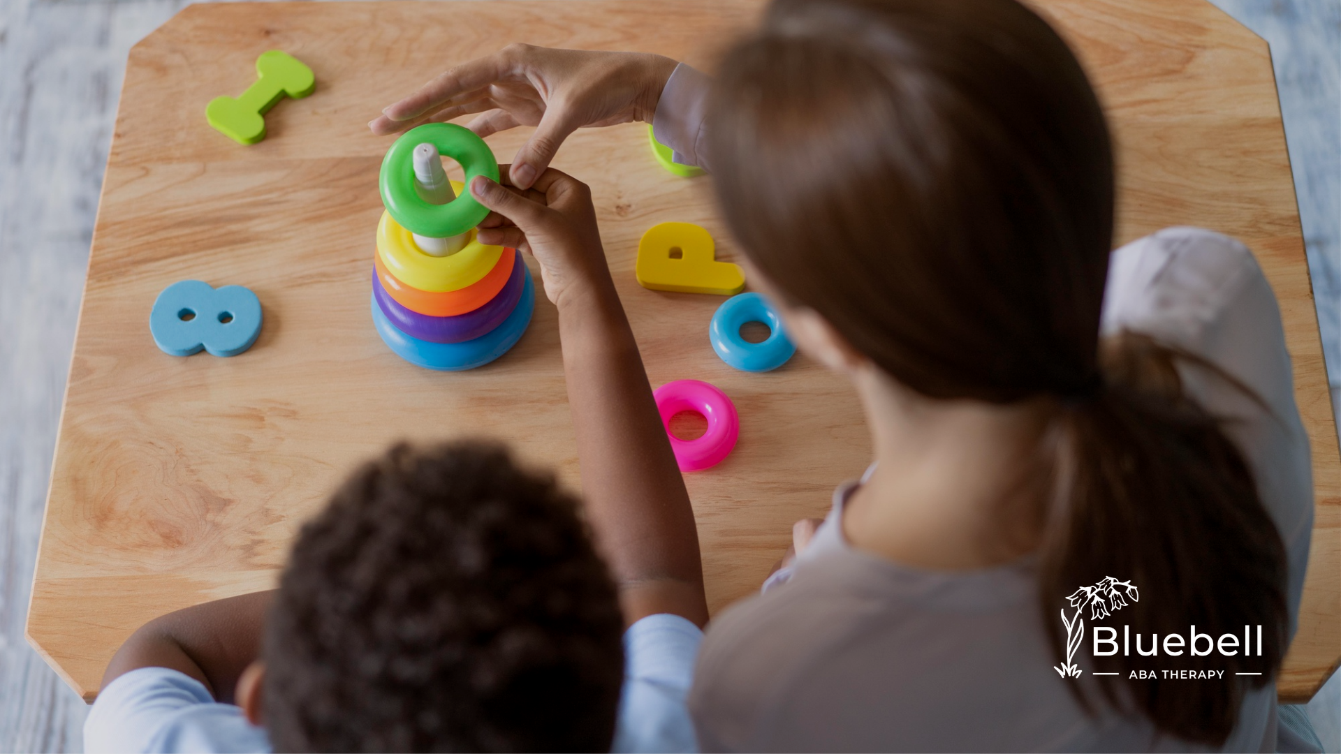A child with autism his ABA therapist playing with colorful toys