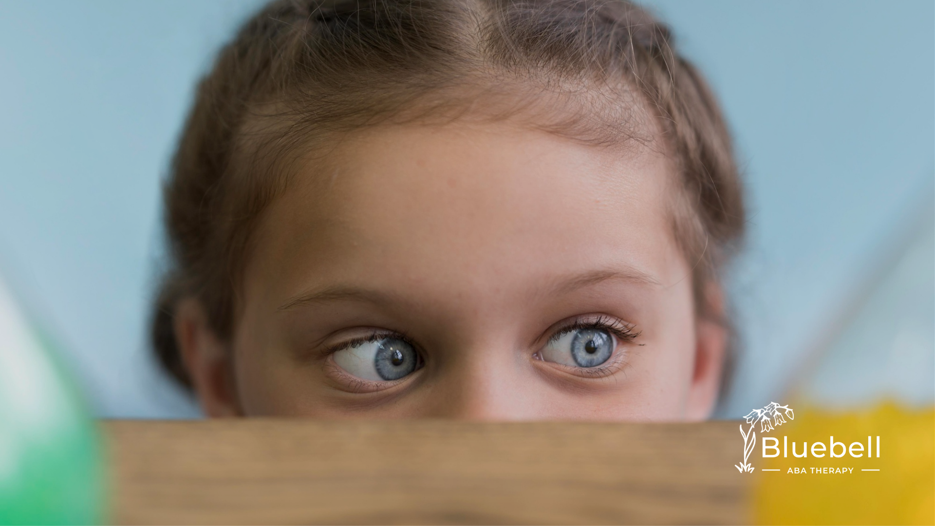 A child with autism hiding by the table avoiding eye contact