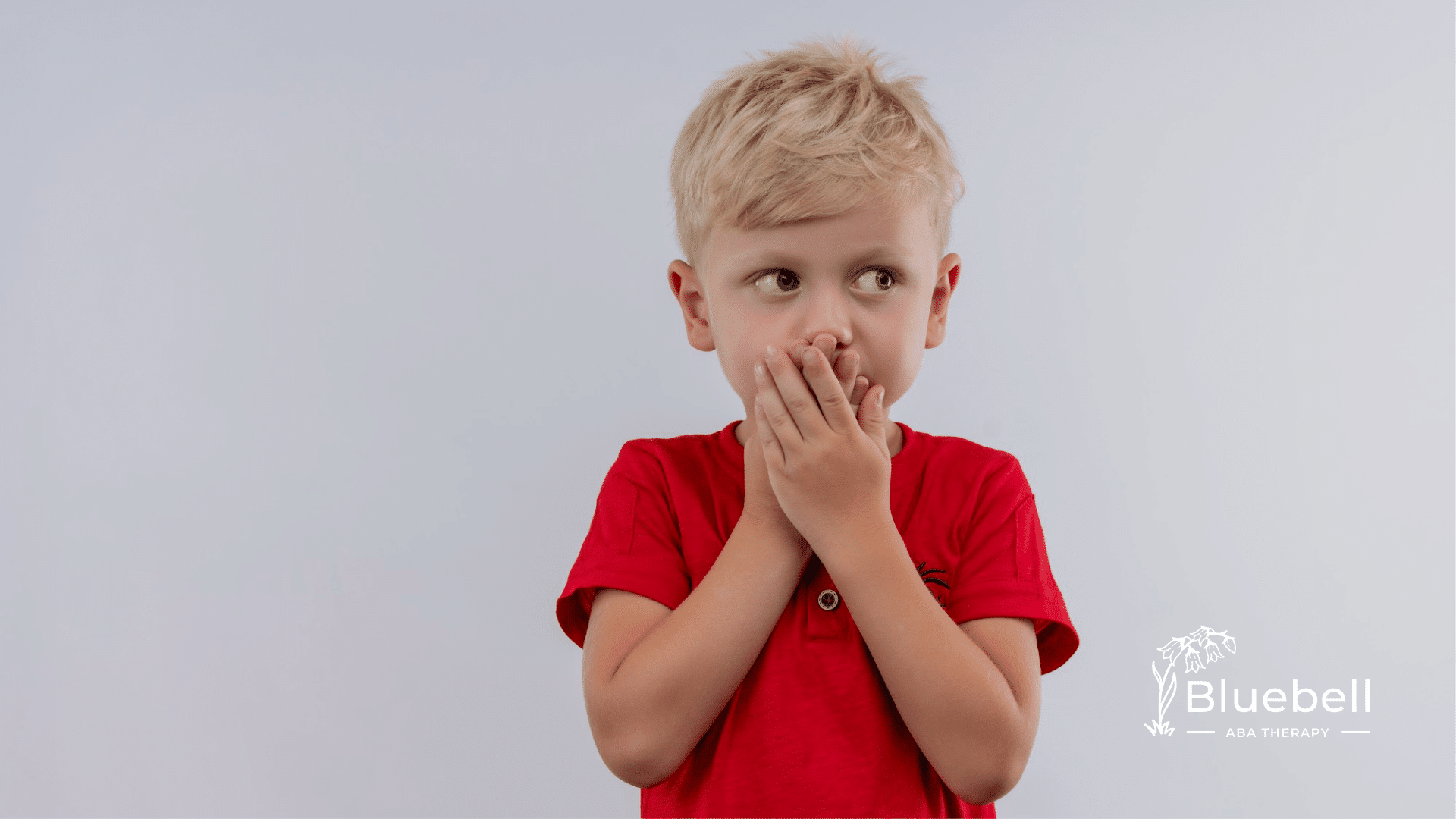 A kid with autism holding his chin and mouth with his two hands