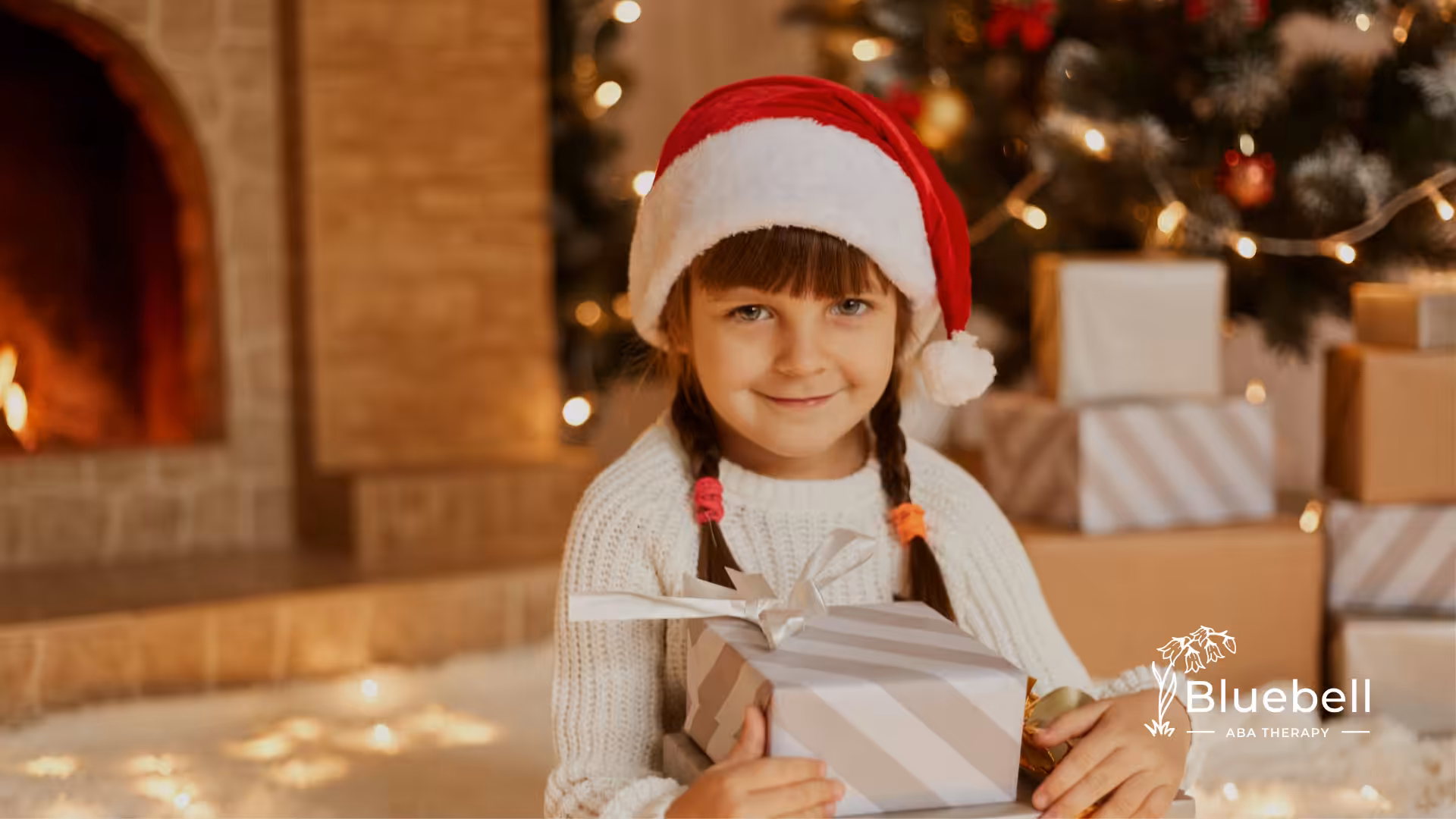 A kid with autism wearing a Santa hat ready to open her Christmas gift