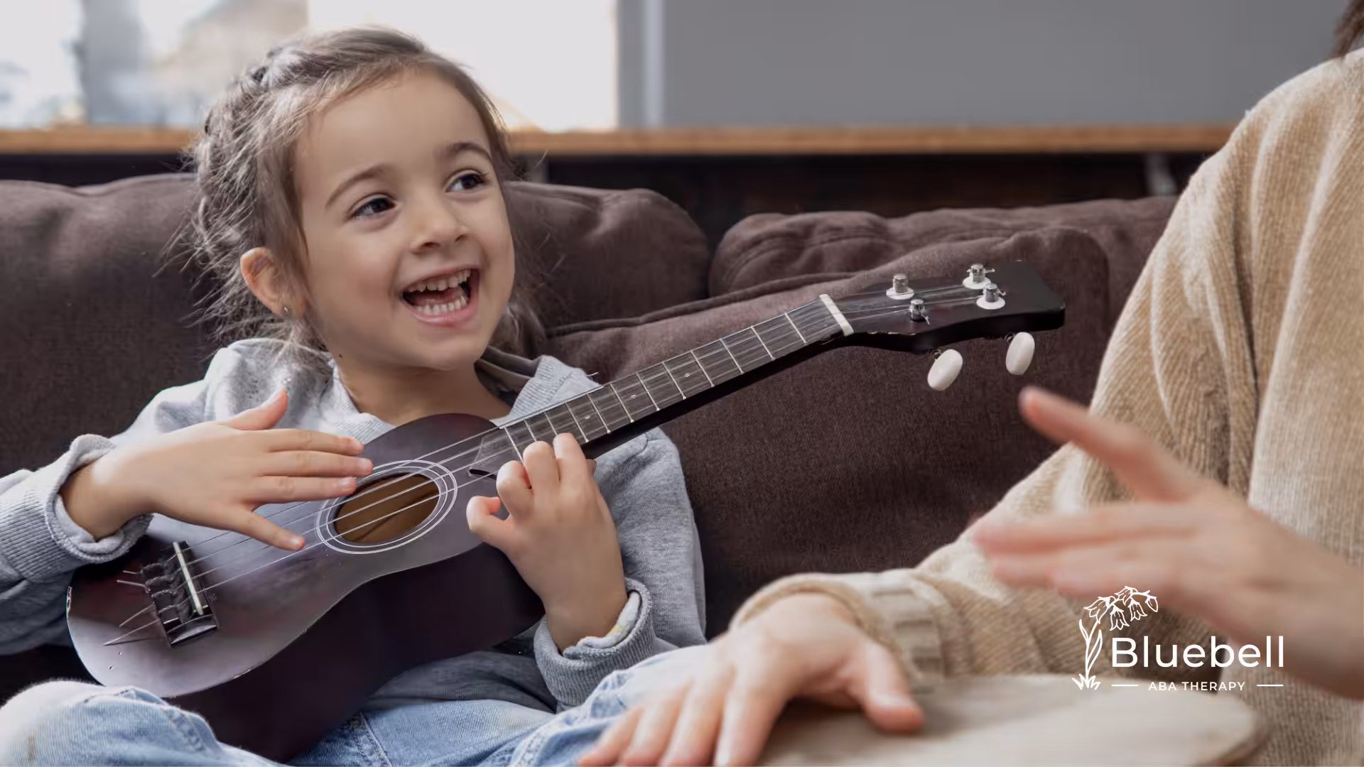 A kid with autism is singing while playing a small guitar