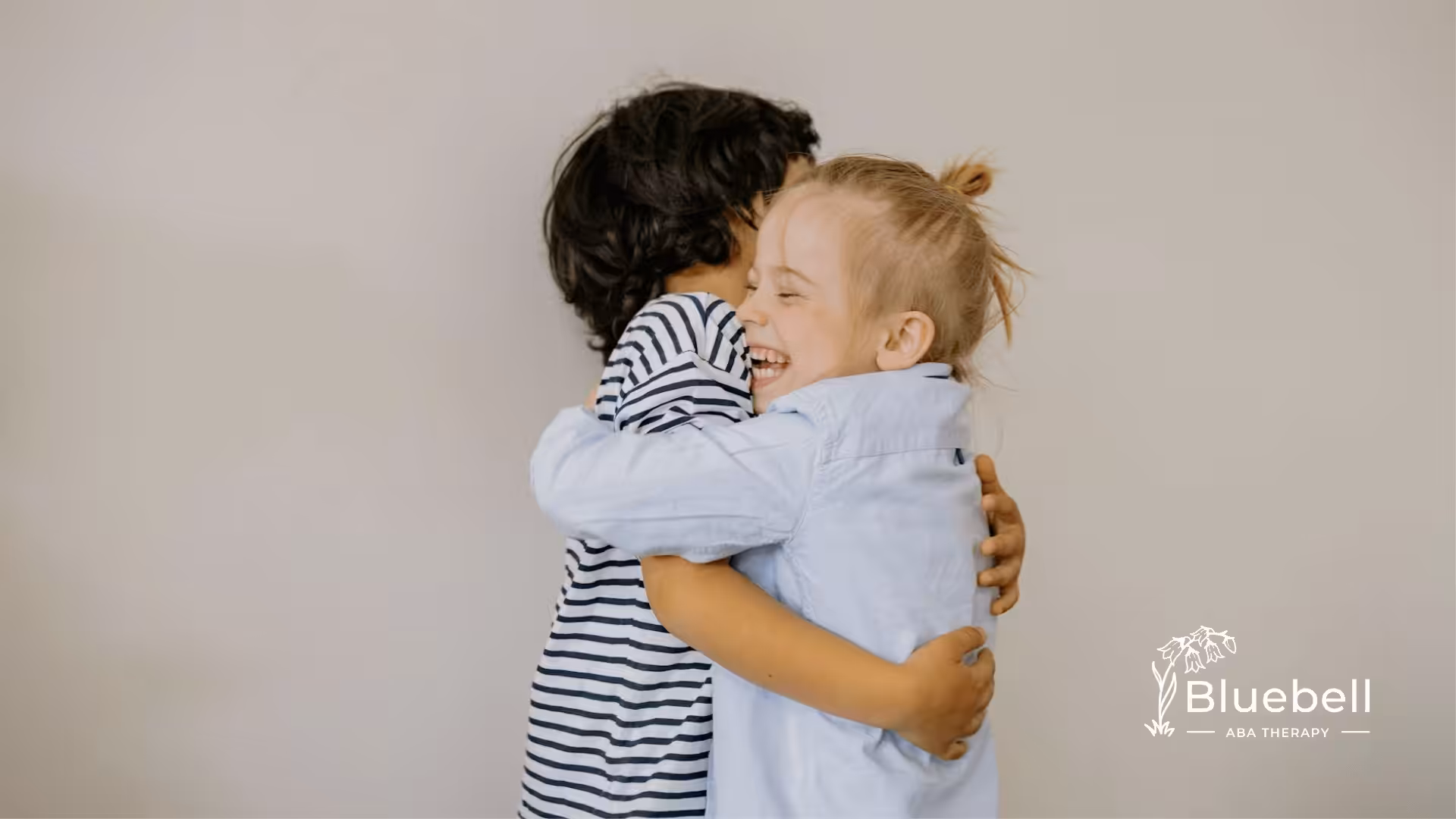 Two joyful autistic children share a warm hug, smiling brightly in a moment of pure connection after ABA therapy.
