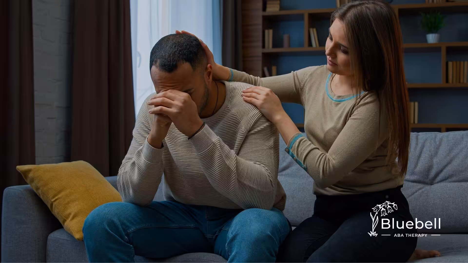 ABA therapist comforting a distressed man on a couch, showing emotional support and regulation during a difficult moment.