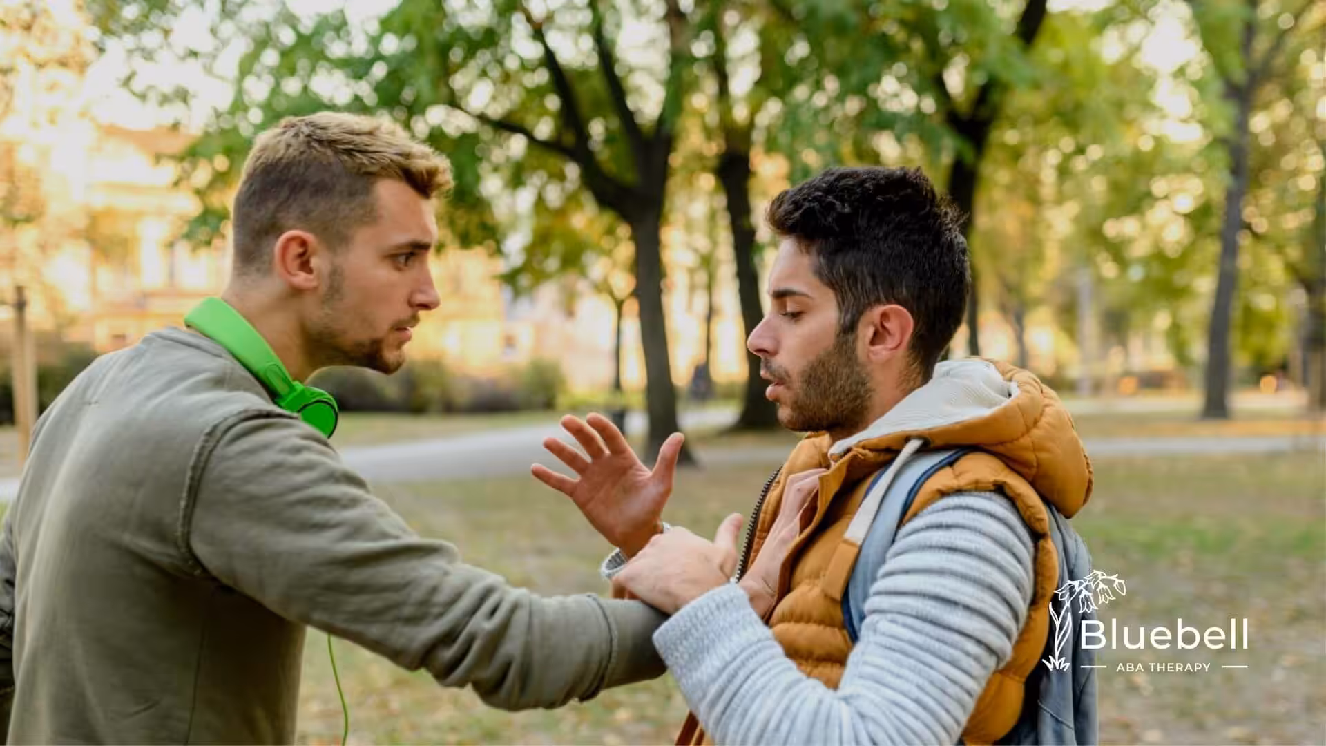 Two boys with autism talking in a park, one reaching out to the other.