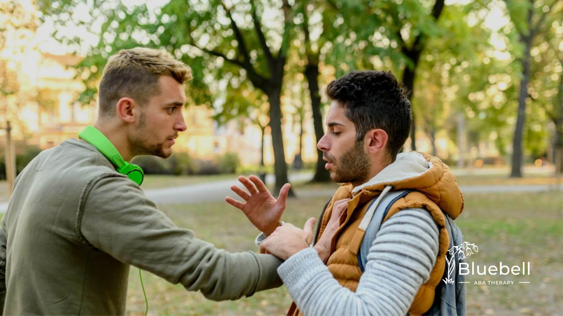 Two boys with autism talking in a park, one reaching out to the other.