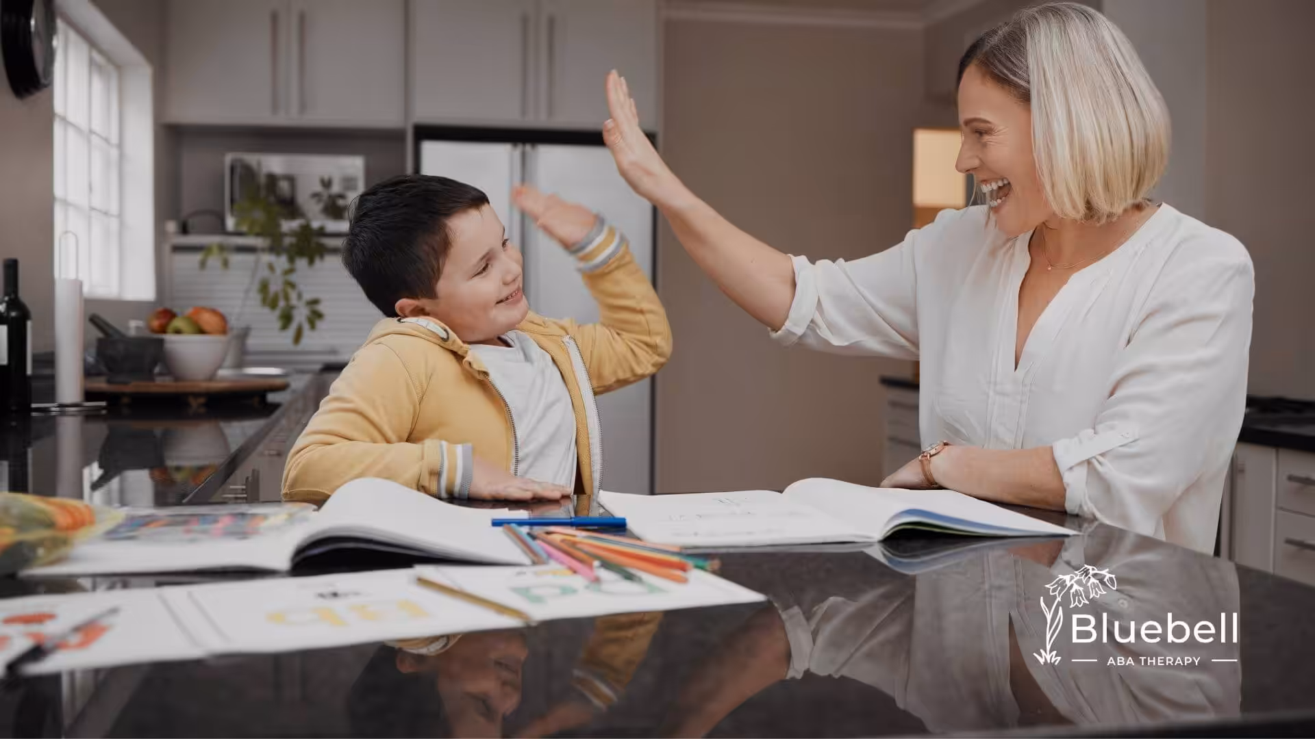 Female therapist giving a high five to autistic girl at a table, reinforcing positive behavior and learning success at home.