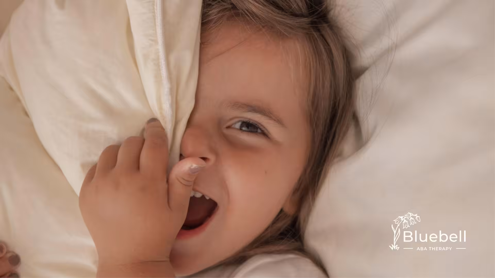A child with autism smiling while holding a pillow.