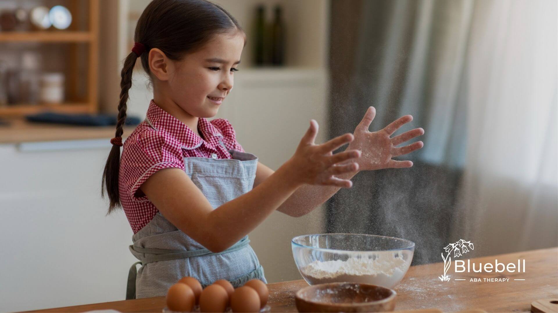 A girl with autism in an apron playing with flour while baking in the kitchen.