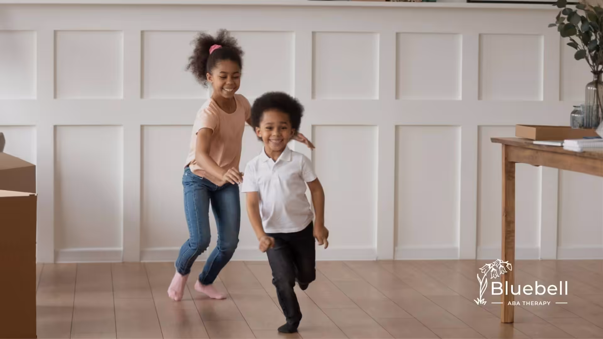 Two young children running and playing inside during center-based ABA therapy.
