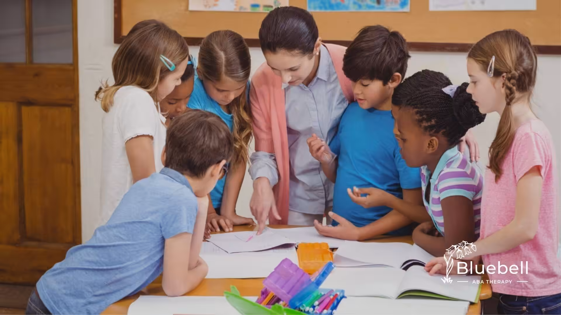 BCBA and a group of young children with autism gathered around a table working on papers together.