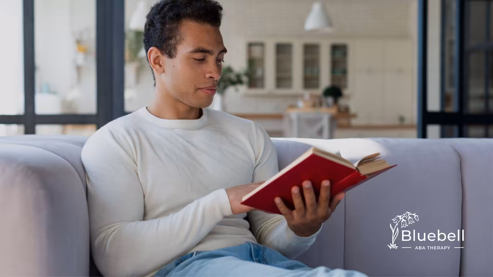 Adult with autism sitting on a couch reading a book.