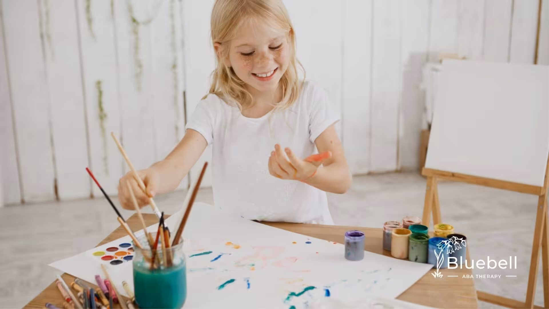 Young girl painting with colorful art supplies during ABA therapy.