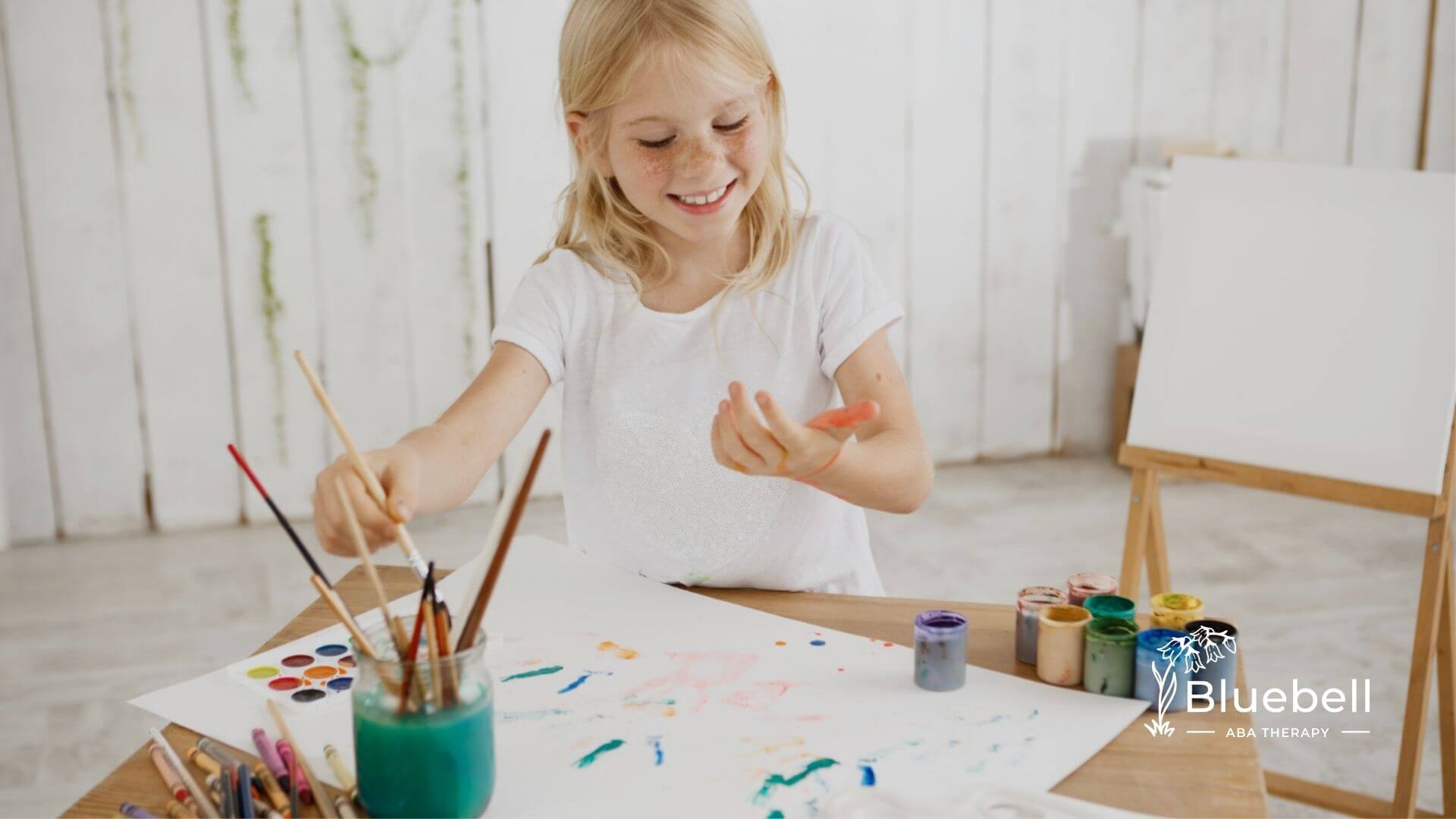 Young girl painting with colorful art supplies during ABA therapy.